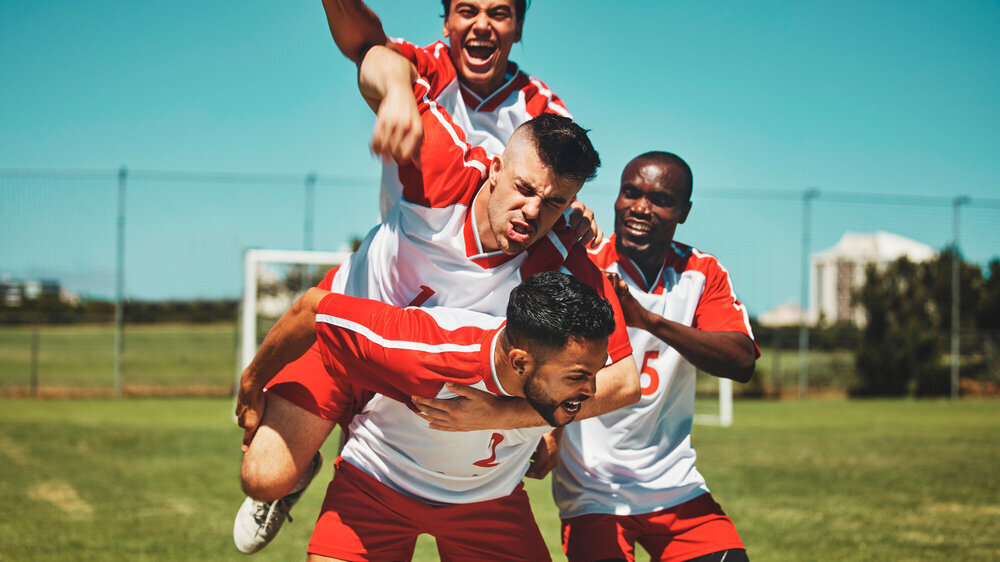 Soccer player, soccer and soccer field, winner and team, diversity and celebrate goal, athlete happy and sports win. Sport, fitness and young men celebrating, outdoor game and team spirit, piggy back Fußballer
