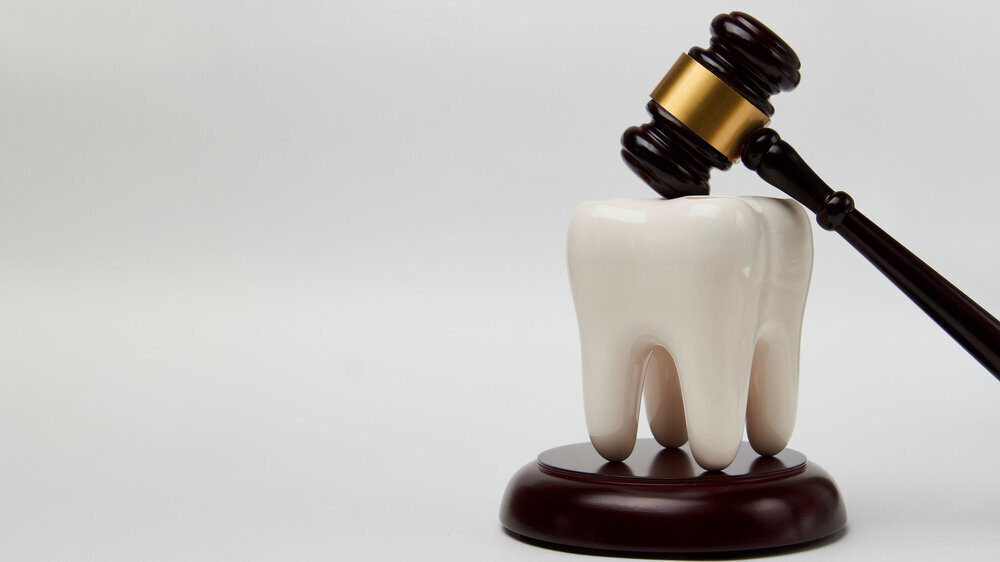 Dental insurance concept. White tooth and judge gavel Urteil Zähne