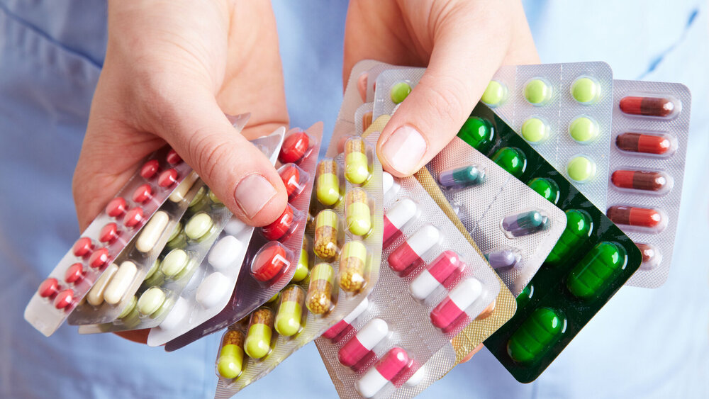 Krankenschwester hält viele bunte Medikamente in den Händen