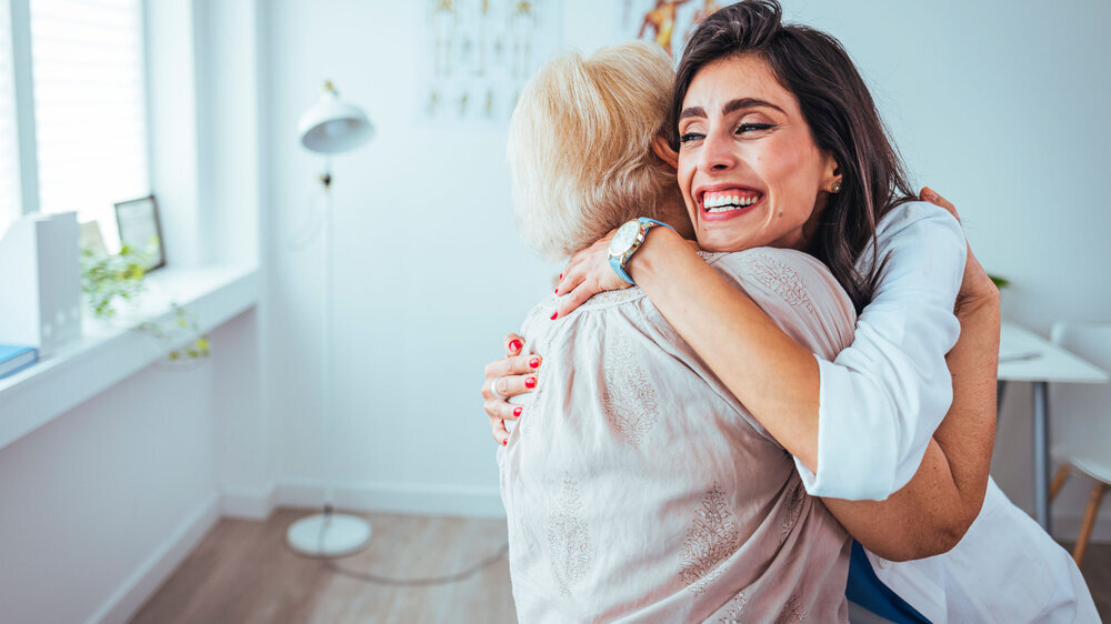 Shot of a young woman doctor hugging her senior patient during a consultation. The proud home healthcare nurse embraces her patient as she provides good news on her improvement. Shot of a young woman doctor hugging her senior patient during a consultation. The proud home healthcare nurse embraces her patient as she provides good news on her improvement.