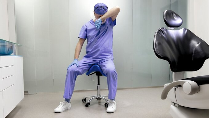 Tired middle age dentist with eyes problem. Having short break for regeneration after long working hours in his office