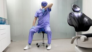 Tired middle age dentist with eyes problem. Having short break for regeneration after long working hours in his office