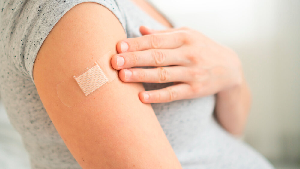 Vaccination of a pregnant woman. Close view of shoulder after vaccine injection with adhesive tape. Covid vaccination concept. Health and medicine during pregnancy.