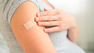 Vaccination of a pregnant woman. Close view of shoulder after vaccine injection with adhesive tape. Covid vaccination concept. Health and medicine during pregnancy.
