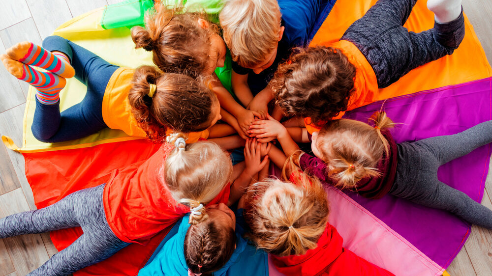 Fröhliche Kinder spielen teambildende Spiele auf einem Fußboden Fröhliche Kinder spielen teambildende Spiele auf einem Fußboden