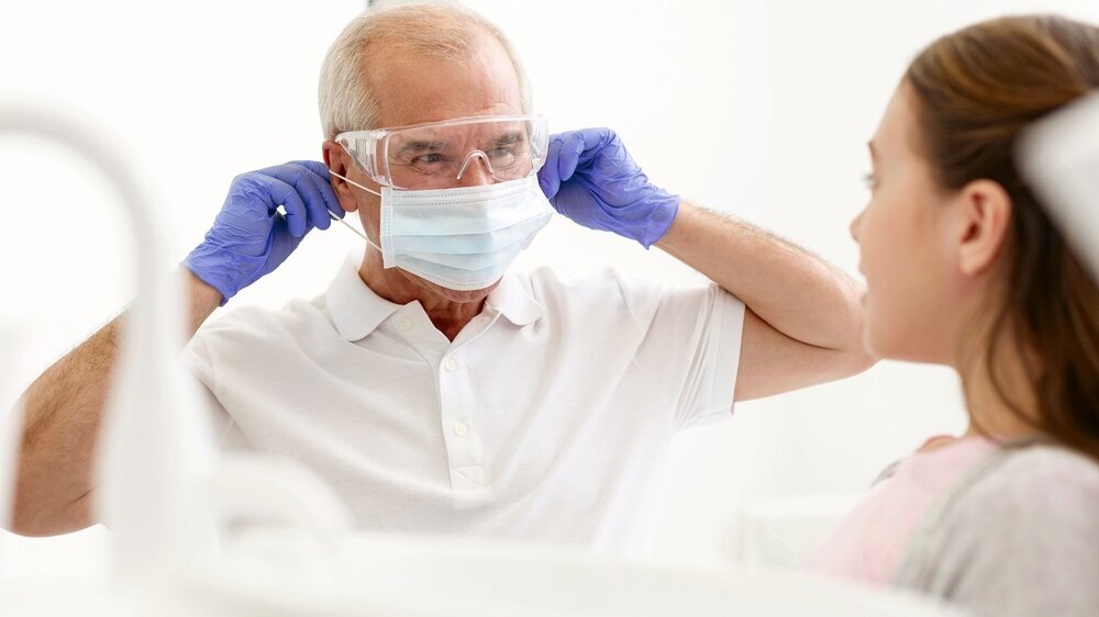 Girl looking at senior dentist wearing mask at dental clinic