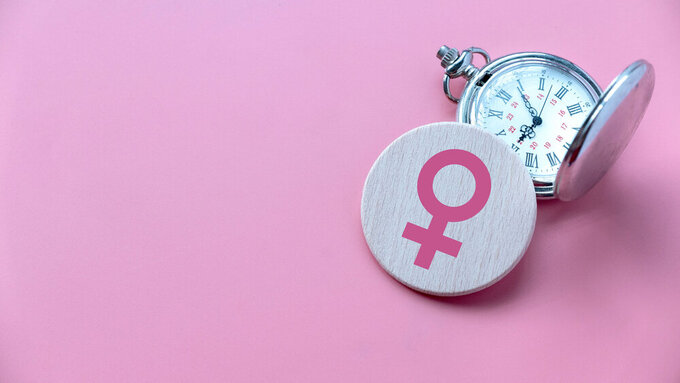 Menopause concept. Women symbol over a watch. Healthcare and medical for women. Pink background with copy space. Menopause
