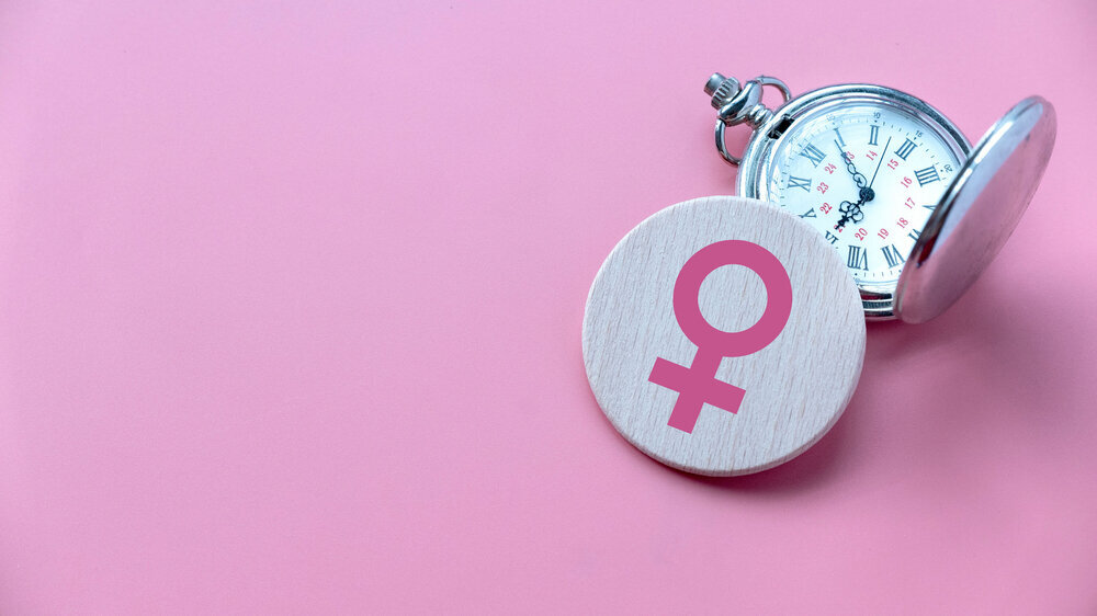 Menopause concept. Women symbol over a watch. Healthcare and medical for women. Pink background with copy space. Menopause