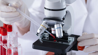 Ein Wissenschaftler untersucht eine Blutprobe auf HIV.