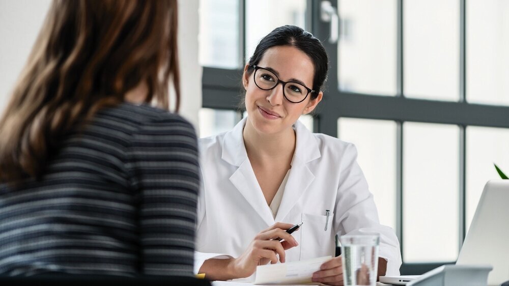 Female physician listening to her patient during consultation Symbolbild Ärztin im Patientengespräch