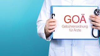 GOÄ (Gebührenordnung für Ärzte). Arzt hält blaues Schild mit Papier.