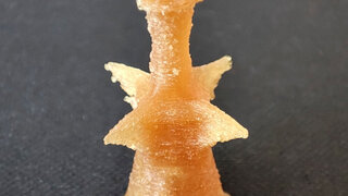 Das Foto zeigt eine bienenwachsfarbene Form, die einer Schachfigur ähnelt. Es handelt sich um eine neuartige Pille aus dem 3D-Drucker.