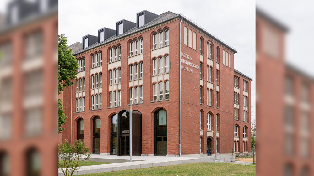 Außenaufnahme des Berliner Medizinhistorischen Museums der Charité (BMM) nach der umfangreichen Modernisierung. Für Licht und Transparenz sorgen die großen Fenstervitrinen. Das Museum befindet sich auf dem Stammgelände der Charité in Berlin Mitte. Aus dem ehemaligen Eingang an der Seite ist ein großes, einladendes Entree geworden. Im Zweiten Weltkrieg wurden das Gebäude und die Sammlung schwer beschädigt. 1998 wurde das Museum als BMM wiedereröffnet und präsentiert seit 2007 die Dauer- sowie zahlreiche Sonderausstellungen, die jährlich gut 90.000 Besuchende anziehen.