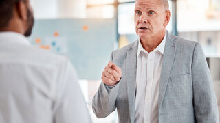 Aggressiver Mann beschwert sich lautstark bei Arzt im Behandlungszimmer.