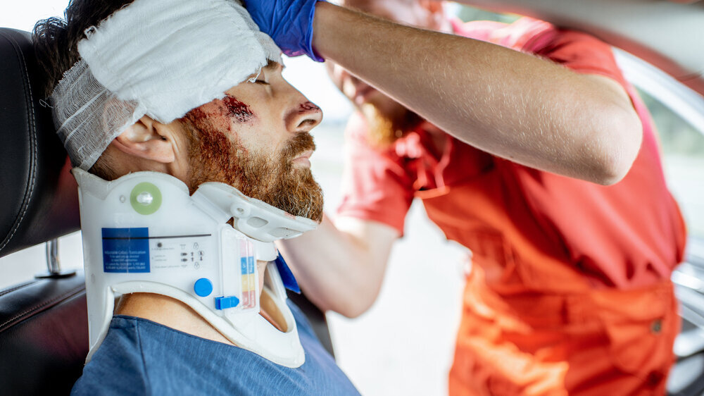 Medic providing emergency medical assistance after the road accident Kopf-Verletzung nach Unfall