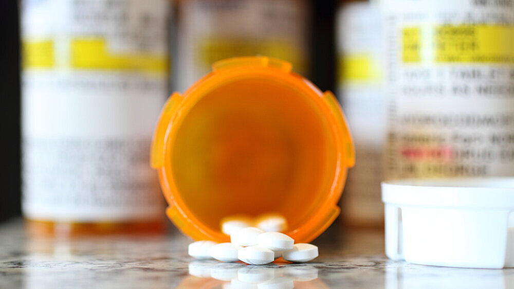 Precription bottles of pain pills on a granite countertop.