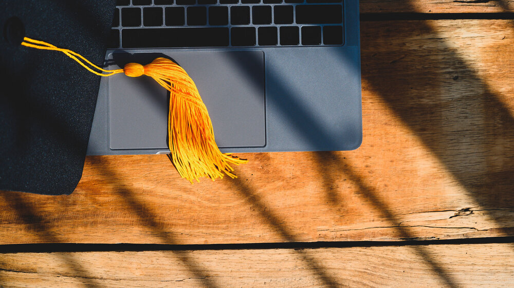 Black Graduation Hat placed on laptop background Promotion