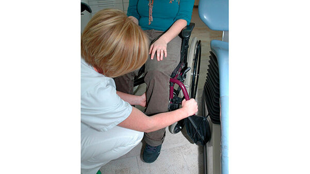 Abb. 2: Die Fußstützen werden entfernt. Dabei müssen die Beine gestützt werden. Die dem Behandlungsstuhl zugewandte Armlehne wird ebenfalls abmontiert. |