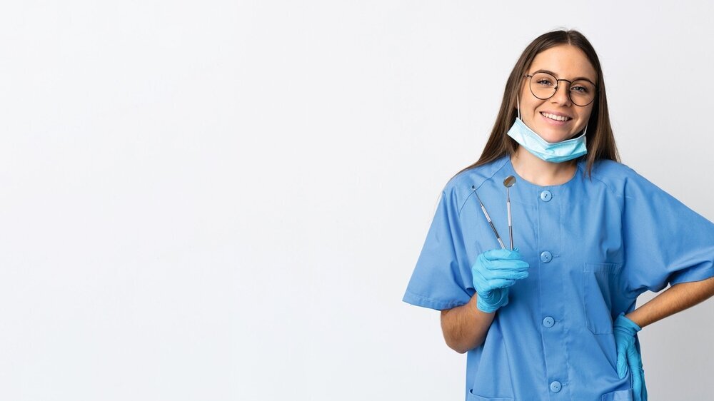 Lithuanian woman dentist holding tools over isolated background posing with arms at hip and smiling ZFA Azubi