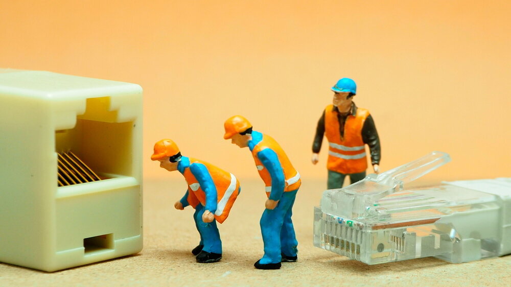 Mini-Actionfigur im Freien mit unscharfem Hintergrund. IT-Ingenieur mit UTP-Kabel.