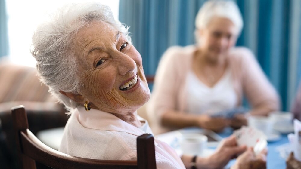 Smiling senior woman playing cards with friends Seniorin