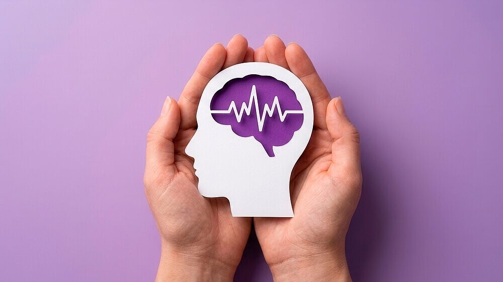 Concept of mental health awareness featuring hands protecting a brain silhouette for epilepsy and autism.