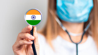 female doctor in a medical mask holds a stethoscope on a light background. Added flag of India. Concept medicine, level of medicine, virus, epidemic. Baner.