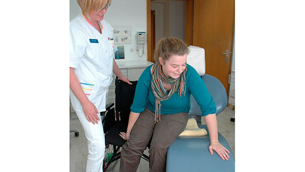 Abb. 3: Soweit es die Selbstständigkeit zulässt, führt die Patientin den Transfer auf den Behandlungsstuhl ohne zusätzliche Hilfe aus. Der Spalt zwischen den Sitzflächen und das Rollstuhlrad können mit einem Kissen oder einer gefalteten Decke abgedeckt werden. |