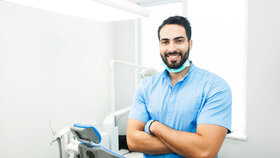 Portrait of hadsome dentist doctor wears blue uniform, indoor shot in modern dentist office