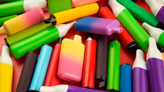 Satz mehrfarbiger elektronischer Einwegzigaretten auf rotem Hintergrund.