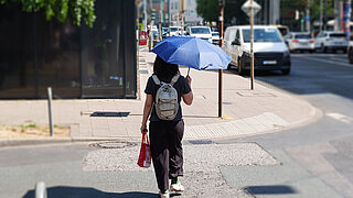 Person nutzt Regenschirm als Sonnenschutz