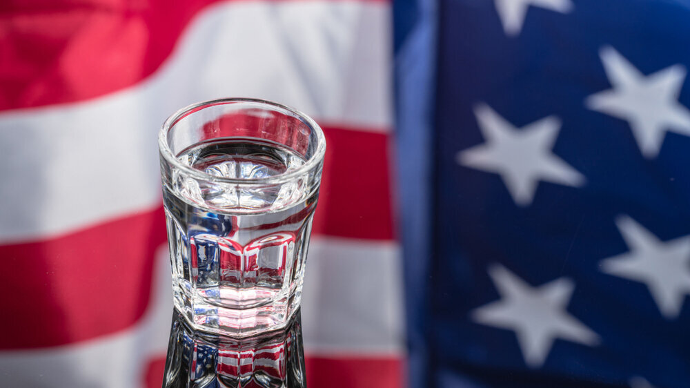 Vodka in shot glass on mirror background with American flag reflected in it. Independence Day Drink Wasserglas USA