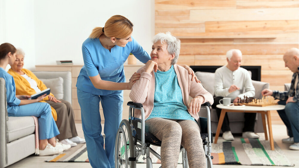 Nurses assisting elderly people at retirement home Krankenschwester mit Rollstuhlfahrerin
