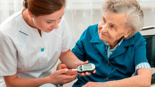 Krankenschwester misst Blutzuckerspiegel bei alter Patientin
