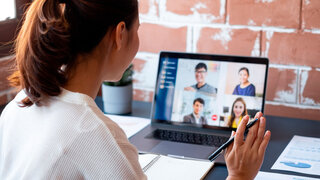 Junge asiatische Geschäftsfrau arbeitet von zu Hause aus und nimmt an einer virtuellen Videokonferenz mit Kollegen aus der Geschäftswelt teil