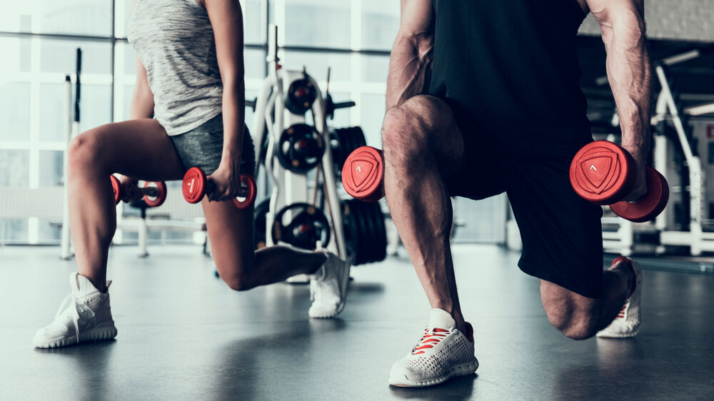 Man and Woman Training in Fitness Club. Man with Athletic Body. Healthy Lifestyle and Sport Concepts. Young Woman in Training Club. Active Indoor Training. Sport Equipment in Club.