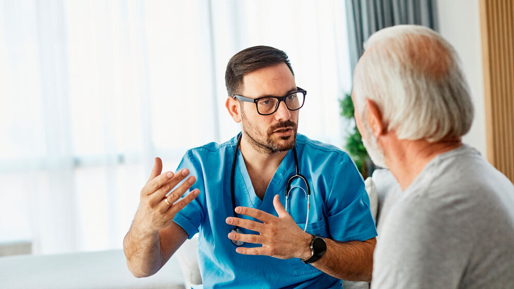 Hausarzt im Gespräch mit älterem Patienten