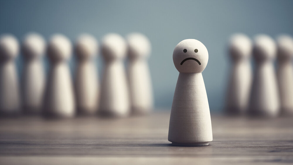 Symbolfoto Mobbing: Eine Spielfigur mit traurigem Gesicht steht abseits einer Gruppe von Spielfiguren. Symbolfoto Mobbing: Eine Spielfigur mit traurigem Gesicht steht abseits einer Gruppe von Spielfiguren.