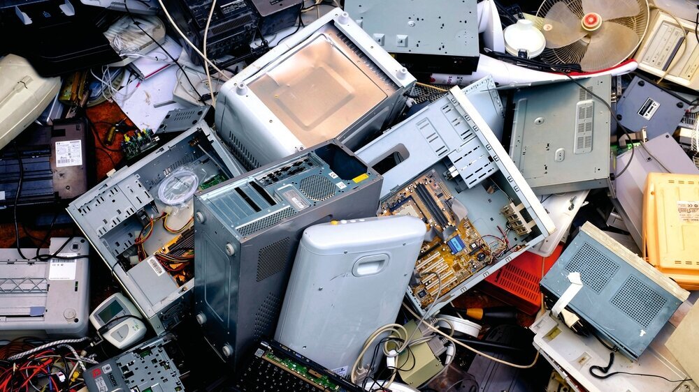 Verschiedene aussortierte Elektrogeräte stapeln sich auf einer Schrottmüllhalde.