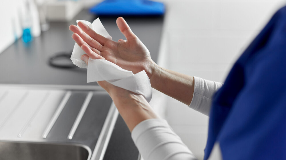 Arzt oder Krankenschwester trocknen sich die Hände mit einem Papiertuch Arzt oder Krankenschwester trocknen sich die Hände mit einem Papiertuch