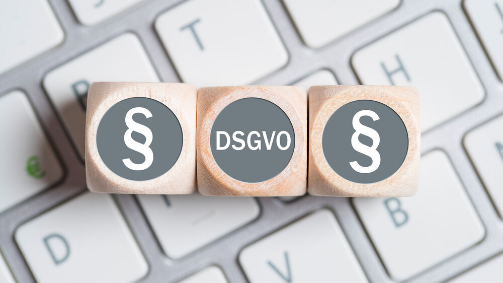 Würfel mit Paragraph Symbolen und Abkürzung DSGVO auf einer Tastatur Urteil DSGVO