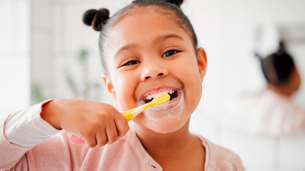 Toothbrush, brushing teeth and face of a child in a home bathroom for dental health and wellness. Smile portrait of african girl kid cleaning mouth with a brush for morning routine and oral self care Mädchen Zähneputzen