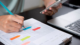 Urlaubsplanung mit Kalender und bunten Post Its.