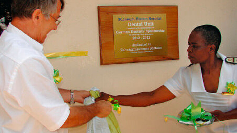 HDZ-Vorsteher, Dr. Klaus Winter bei der offiziellen Einweihung der Zahnstation in Simbabwe. Das Schild am Eingang trägt auch eine Widmung für die sächsische Zahnärztekammer. |