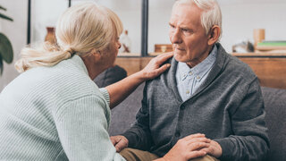 retired couple holding hands and looking at each other at home