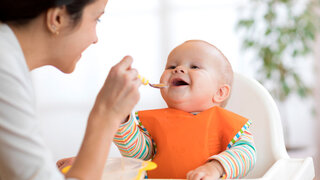 Mutter füttert ihr Baby mit einem Löffel.
