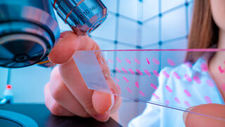 Junge Technikerin untersucht eine histologische Probe, eine Biopsie im Labor für Krebsforschung