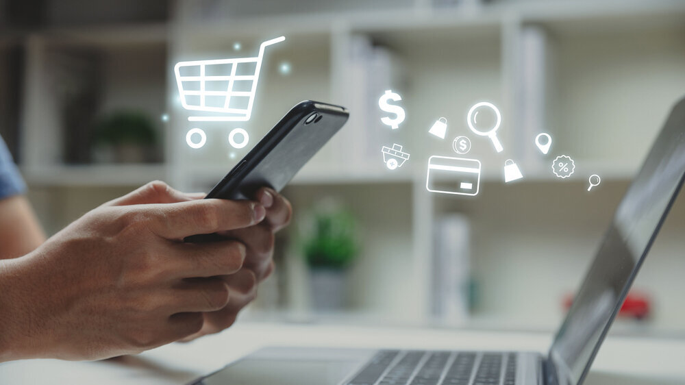Young man using smartphone with shopping cart icon. Symbolbild Internetshopping