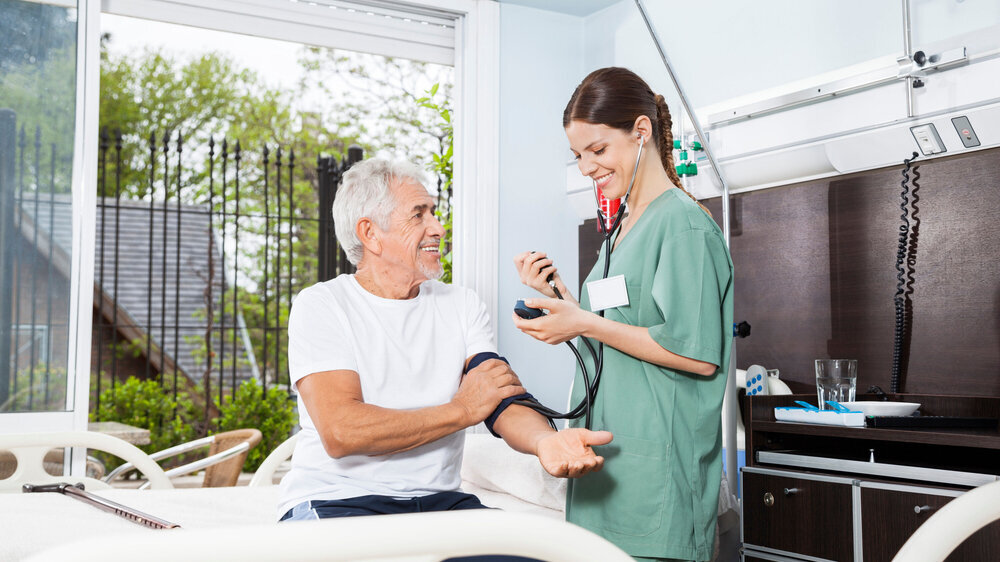 Pflegekraft misst Blutdruck bei älterem Patienten Pflegekraft misst Blutdruck bei älterem Patienten