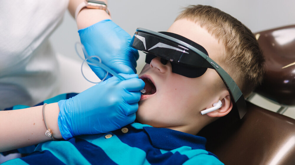 Close up of little boy sitting in dentist in vr glasses and wireless headphones while dentist make x-ray of teeth Nahaufnahme eines kleinen Jungen, der beim Zahnarzt mit VR-Brille und Kopfhörern beim Zahnarzt sitzt.